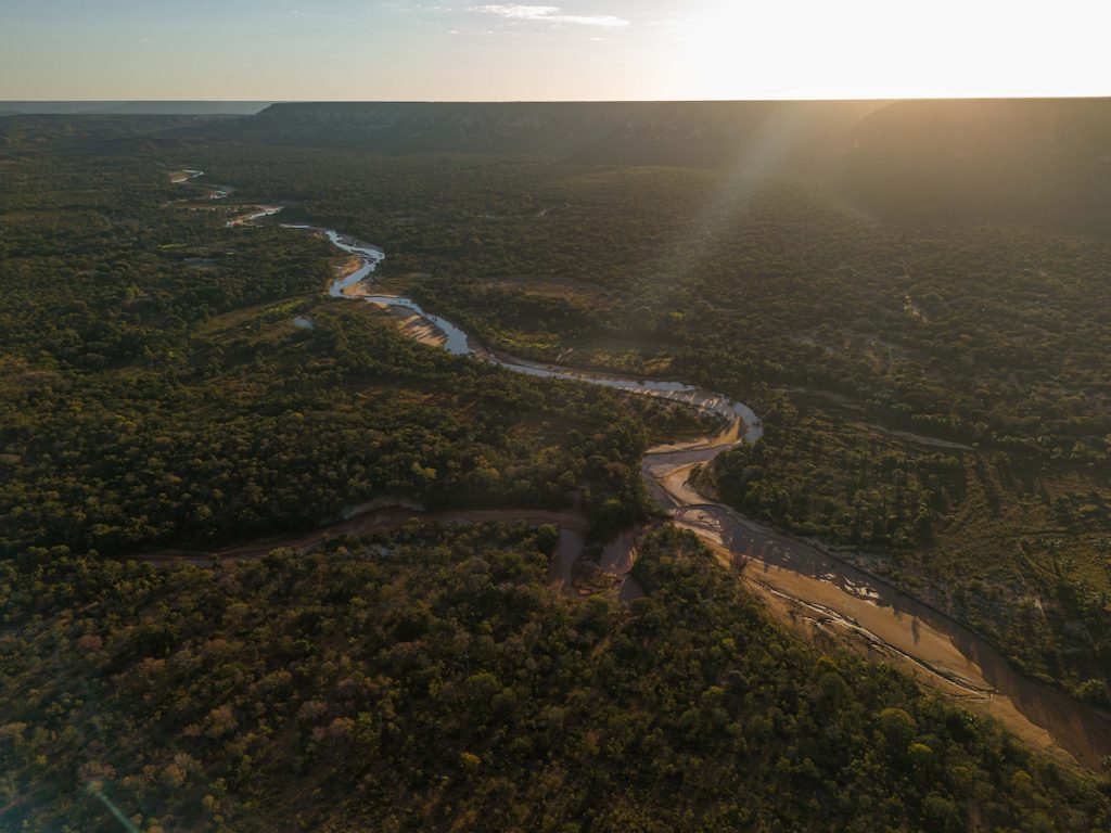 Vista aérea do rio Urucuia serpenteando pelo cerrado ao pôr do sol