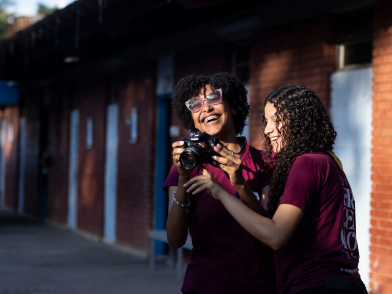 Moradores Educação: estudantes sorridentes conferem foto na câmera