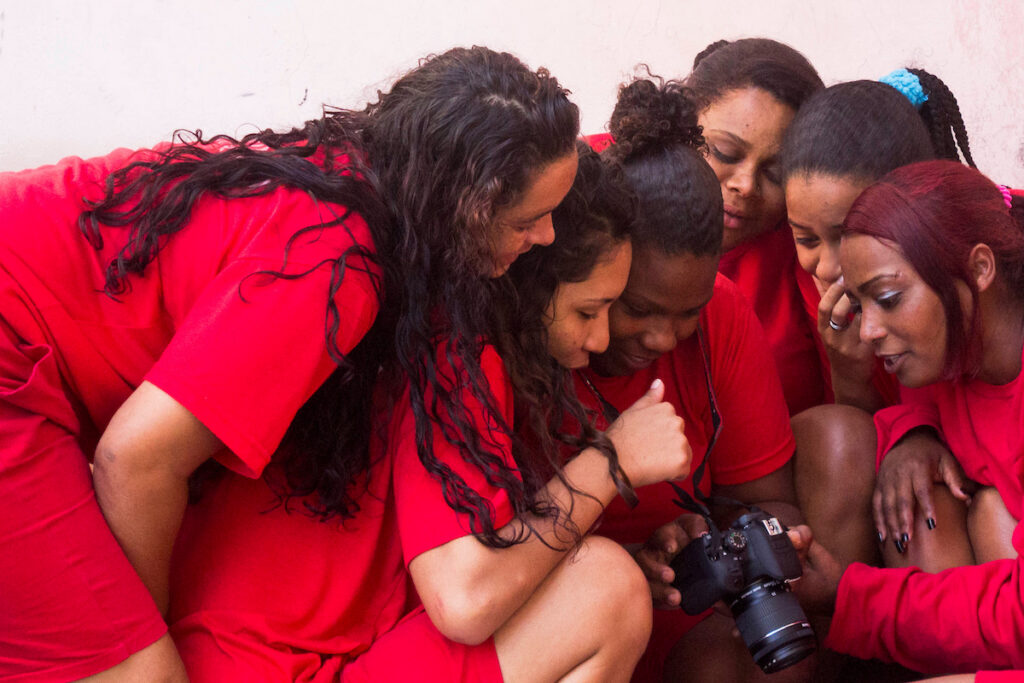 A Estrela: participantes de uniforme vermelho conferem foto na câmera durante oficina