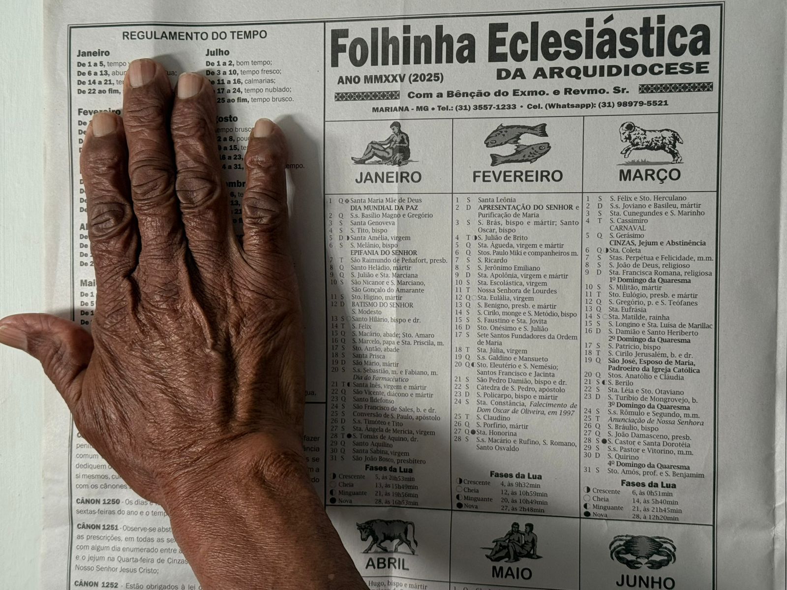 Mão envelhecida sobre a Folhinha Eclesiástica da Arquidiocese de Mariana