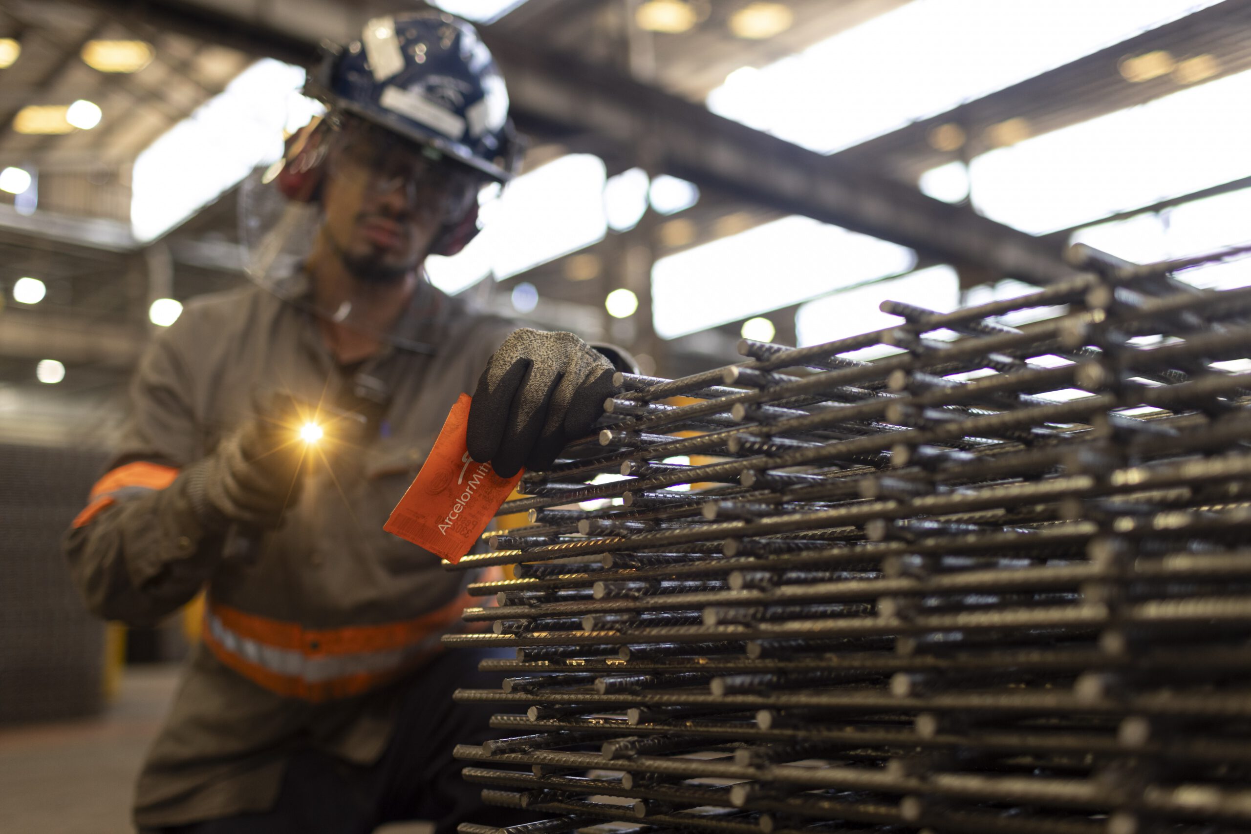 Trabalhador com lanterna inspeciona telas de aço na Trefilaria da ArcelorMittal em São Paulo
