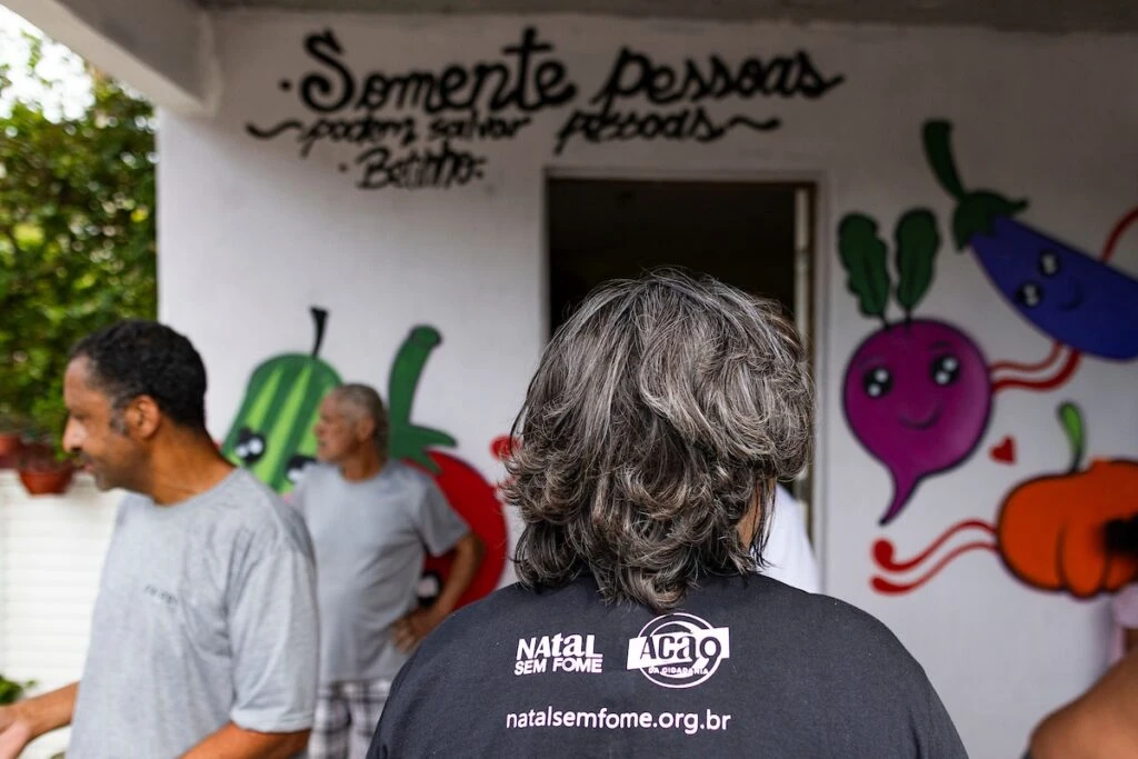 Ação da Cidadania, Natal Sem Fome: voluntária diante de cozinha comunitária com muro grafitado