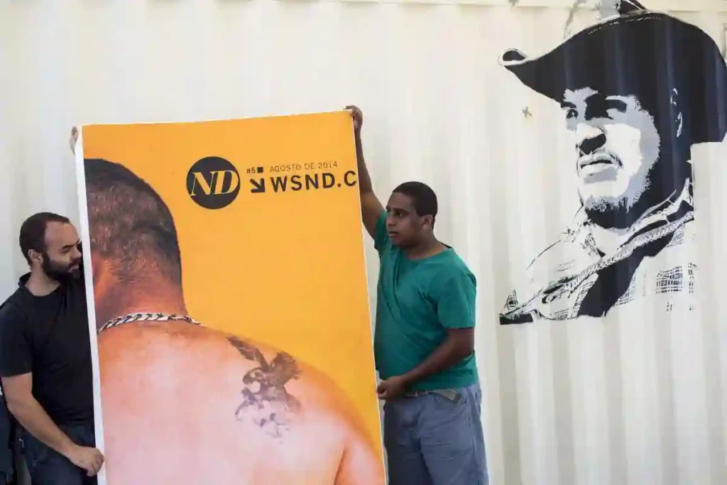 ND: novas possibilidades narrativas: participantes seguram banner diante de mural com retrato