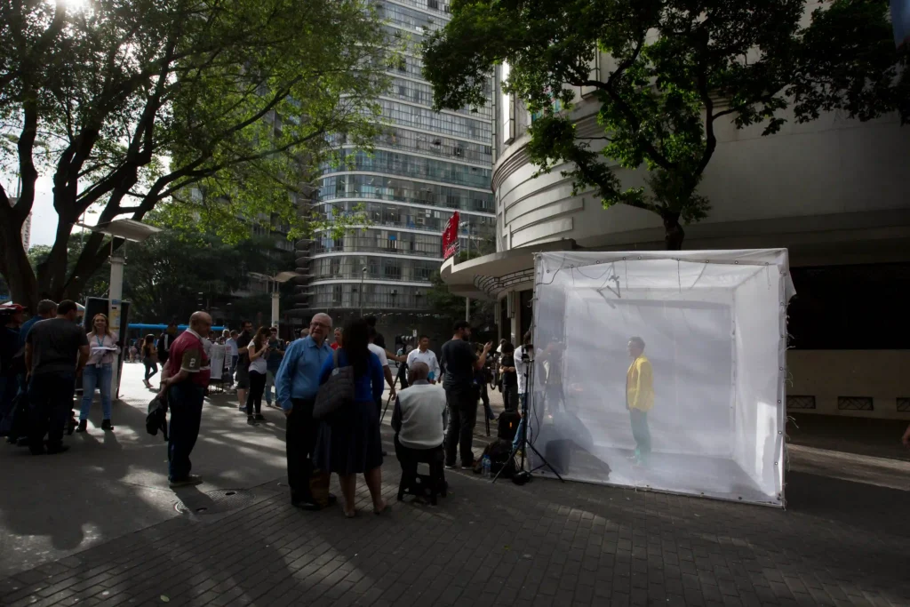 Projeto Moradores: cubo de exposição com retrato em praça movimentada no centro da cidade
