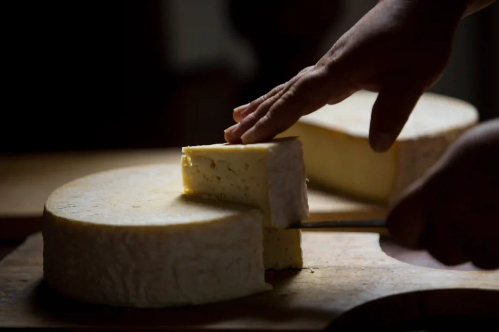 Queijo, Minas Gerais: mãos cortam fatia de queijo minas artesanal