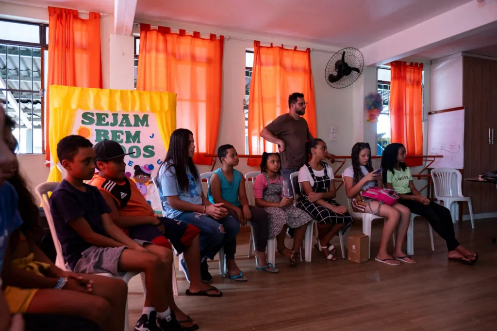 GCriva: crianças sentadas em roda em sala colorida