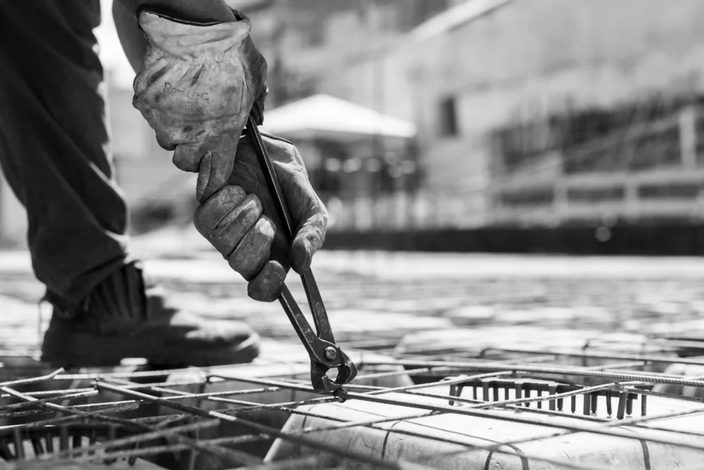 Relatório MRV&CO: mãos com luva amarram vergalhões