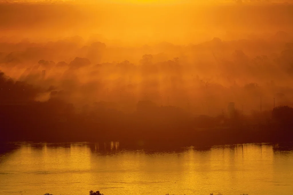 Os Chicos: pôr do sol alaranjado refletido no rio