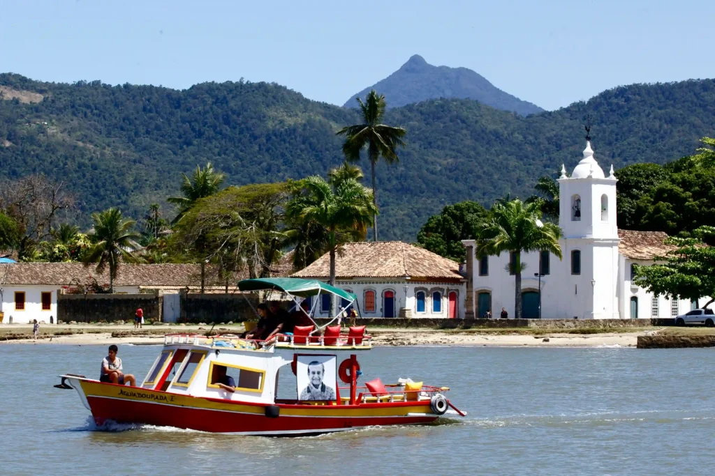 Projeto Moradores em Paraty: barco com retrato navegando diante da igreja e das montanhas