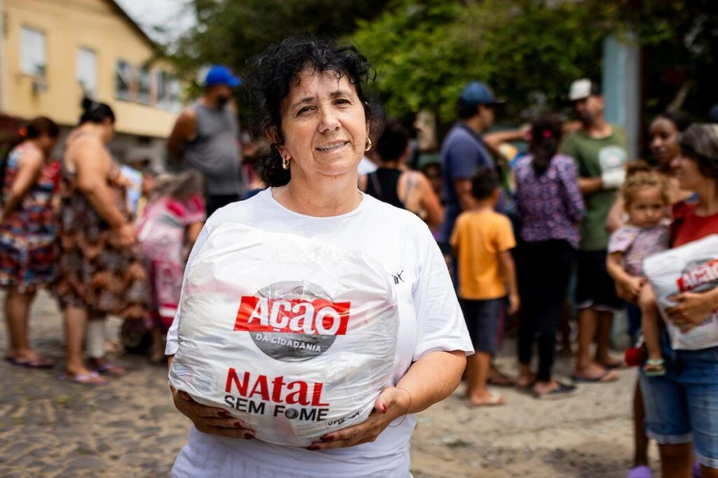 Ação da Cidadania, Natal Sem Fome: mulher segura sacola de doação diante da fila