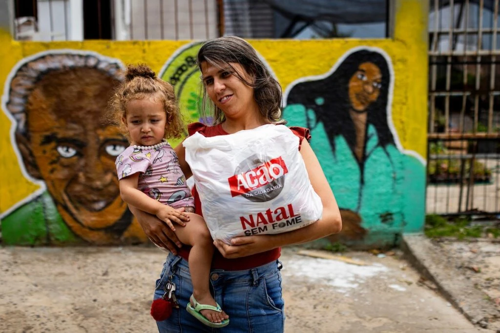 Ação da Cidadania, Natal Sem Fome: mãe com bebê no colo segura sacola de doação