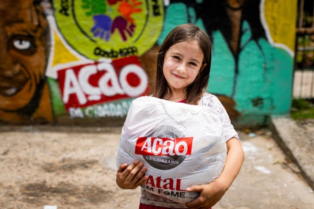 Ação da Cidadania, Natal Sem Fome: menina sorridente segura sacola de doação