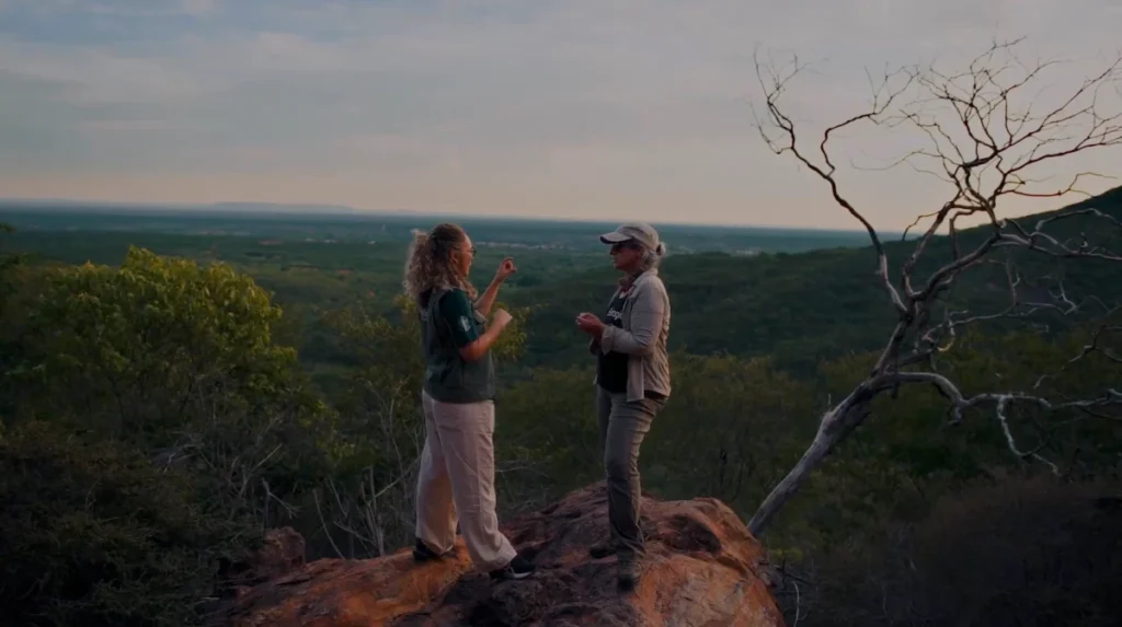 ANTA – O filme: pesquisadoras conversam sobre rocha com vista para o cerrado ao entardecer