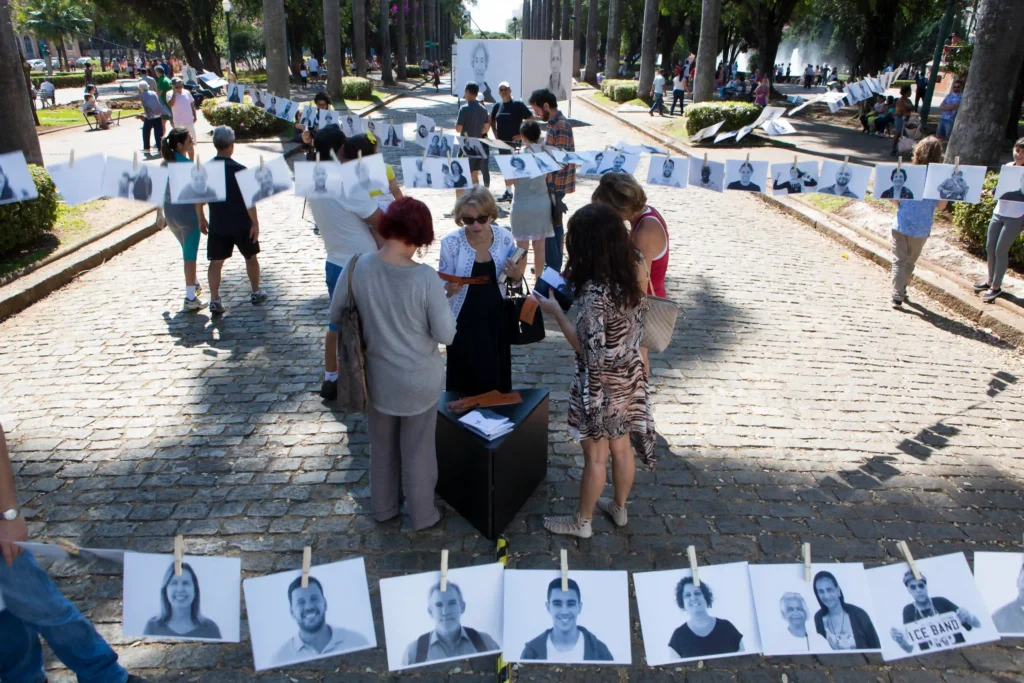 Projeto Moradores: varal de retratos dos moradores estendido em rua de pedra com público
