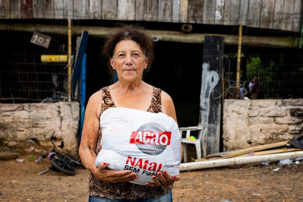 Ação da Cidadania, Natal Sem Fome: senhora segura sacola de doação em quintal