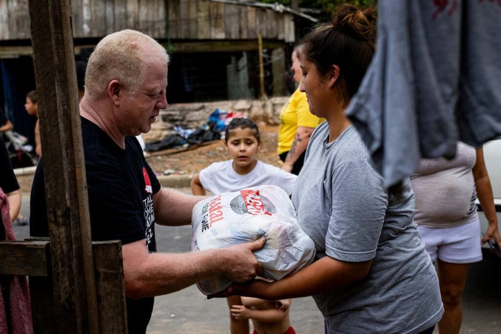 Ação da Cidadania, Natal Sem Fome: voluntário entrega sacola de doação a moradora