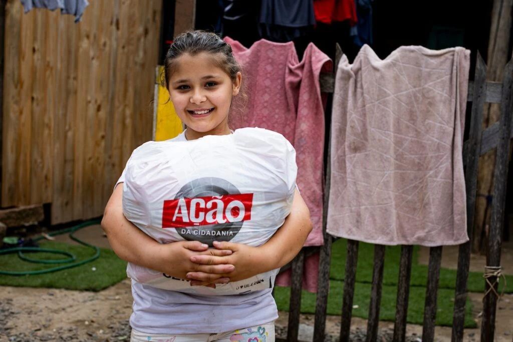 Ação da Cidadania, Natal Sem Fome: menina sorridente abraça sacola de doação