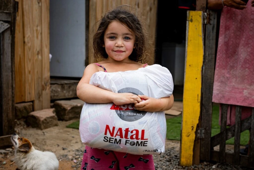 Ação da Cidadania, Natal Sem Fome: menina segura sacola de doação no quintal