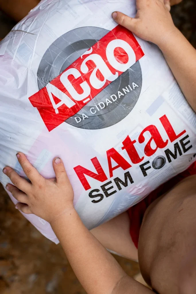 Ação da Cidadania, Natal Sem Fome: mãos de criança abraçando sacola de doação, vista de cima