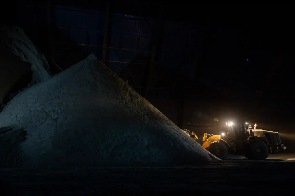 Lundin Mining: pilha de minério à noite com máquina iluminada ao fundo