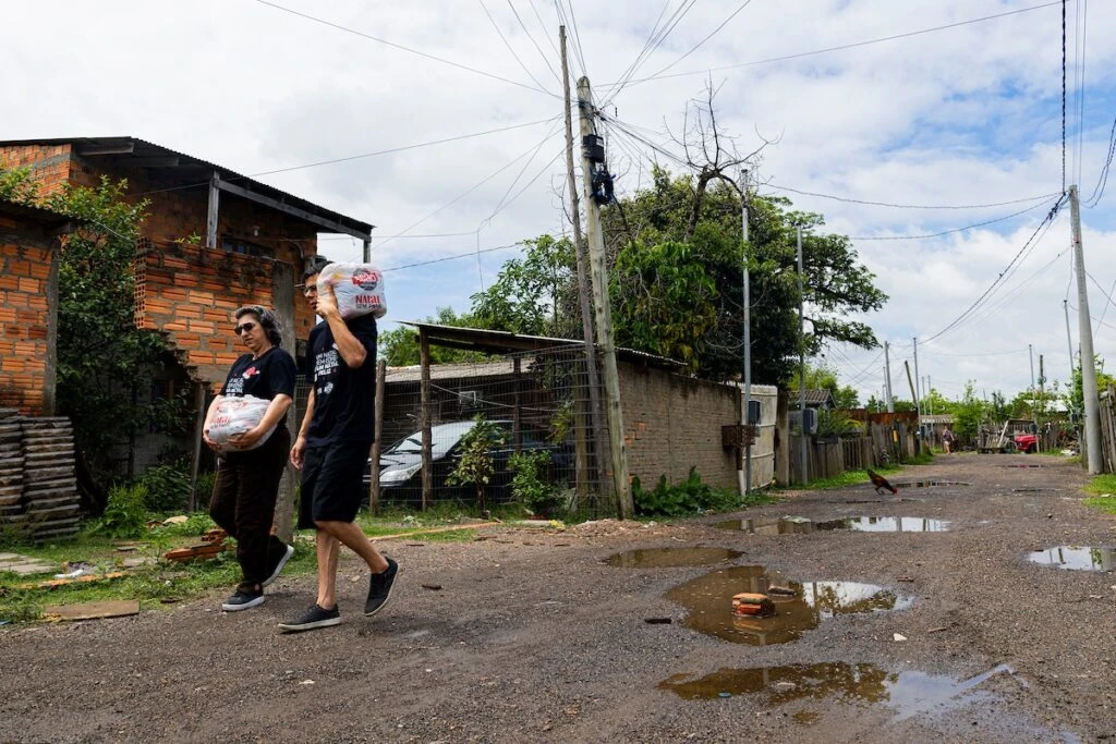 Ação da Cidadania, Natal Sem Fome: voluntários caminham com sacolas por rua de terra