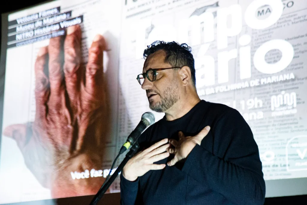 Exibição de Tempo Vário em Mariana: diretor fala ao público diante do cartaz do filme