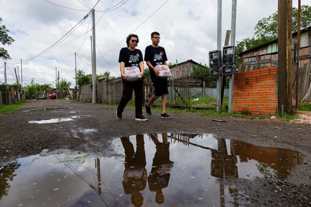 Ação da Cidadania, Natal Sem Fome: voluntários com sacolas refletidos em poça d'água