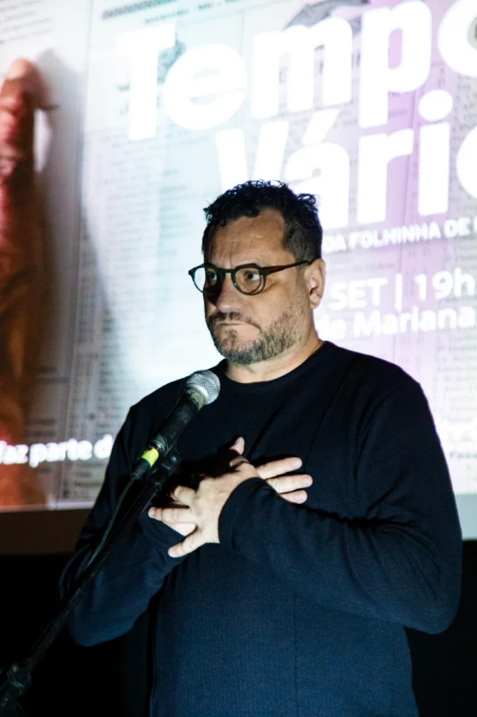 Exibição de Tempo Vário em Mariana: diretor fala ao microfone diante do cartaz do filme