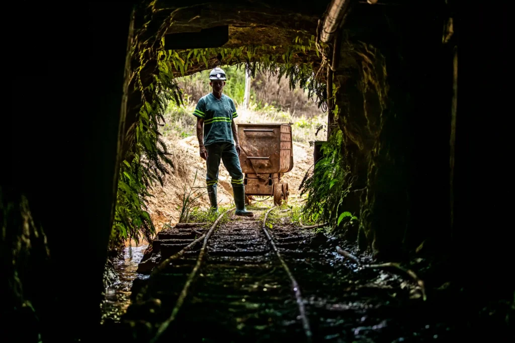 Mina do Cruzeiro: minerador na entrada de túnel com trilhos e vagonete