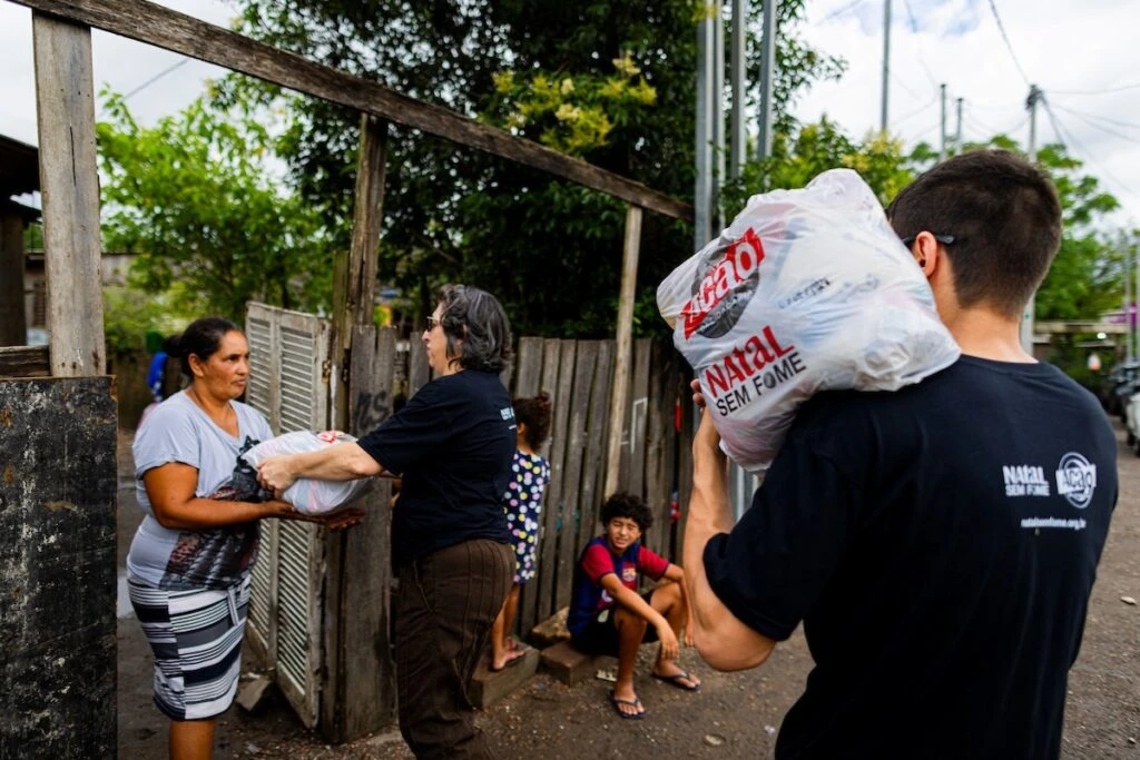 Ação da Cidadania, Natal Sem Fome: voluntário com sacola no ombro enquanto outra entrega doação