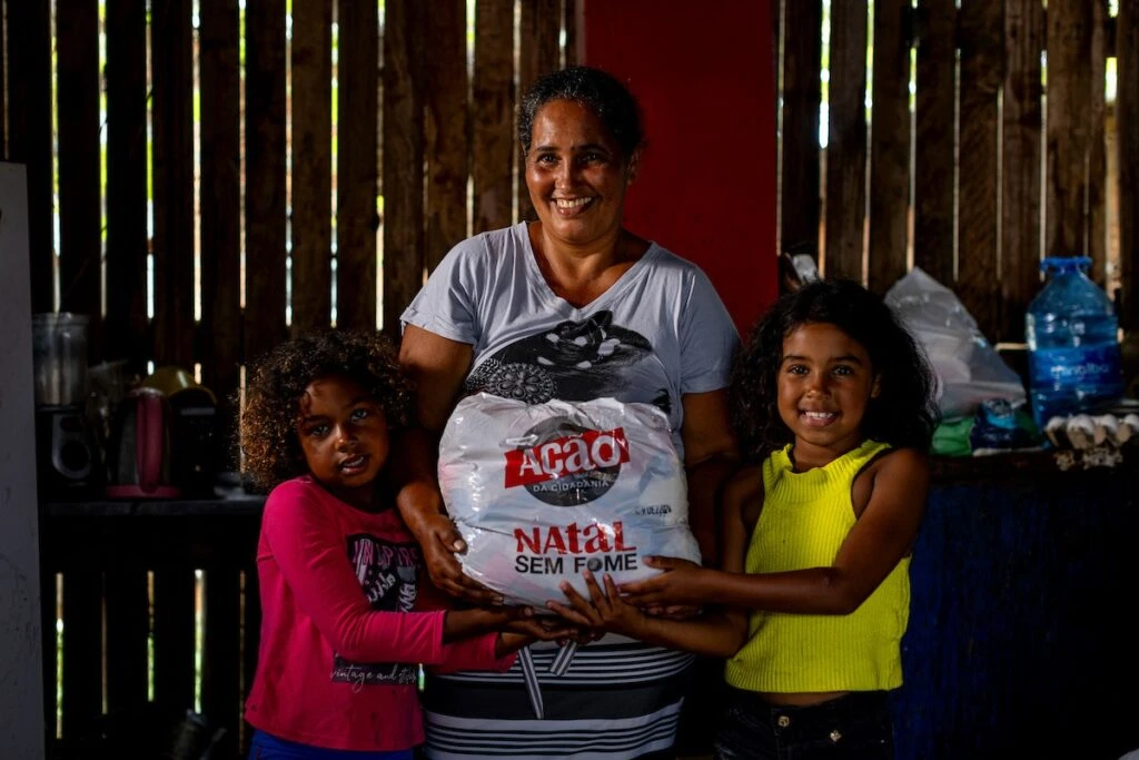Ação da Cidadania, Natal Sem Fome: mãe e filhas sorridentes com sacola de doação