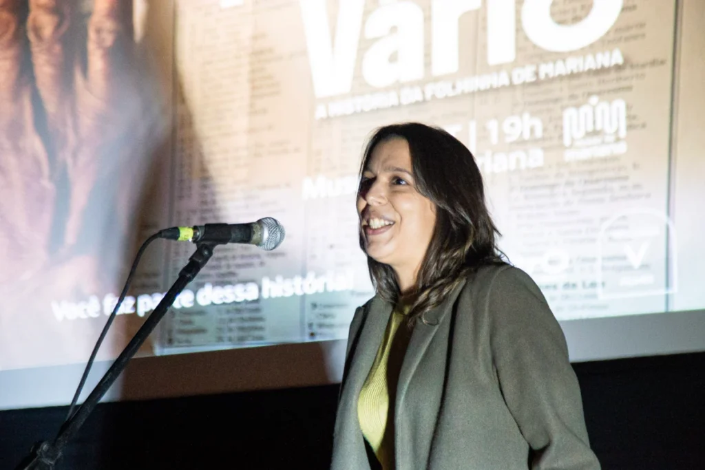 Exibição de Tempo Vário em Mariana: convidada fala ao público diante do cartaz do filme