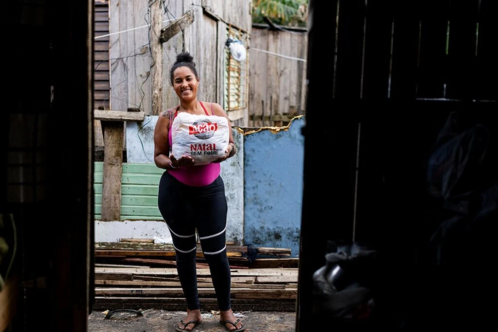 Ação da Cidadania, Natal Sem Fome: moradora sorridente segura sacola de doação