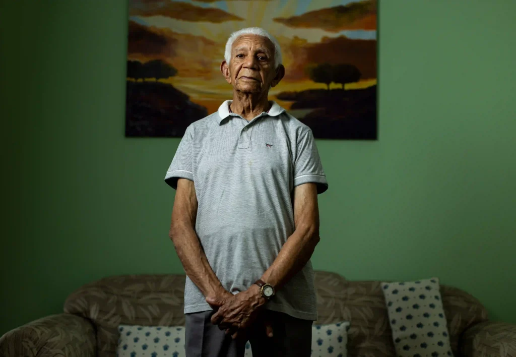 Centenários: retrato de senhor centenário em pé diante de parede verde