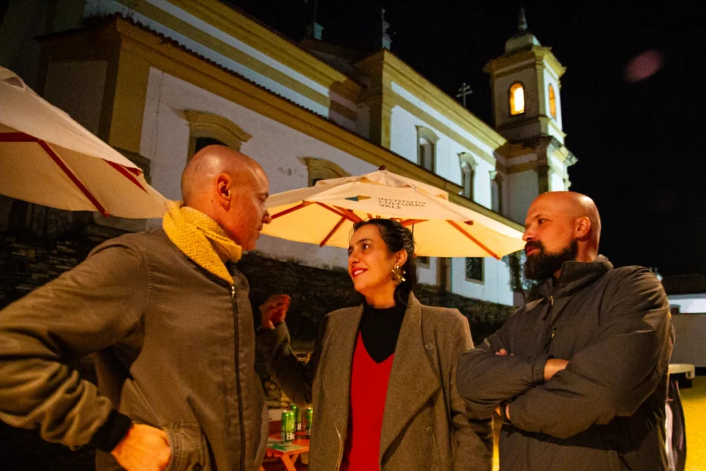 Exibição de Tempo Vário em Mariana: convidados conversam diante de igreja iluminada