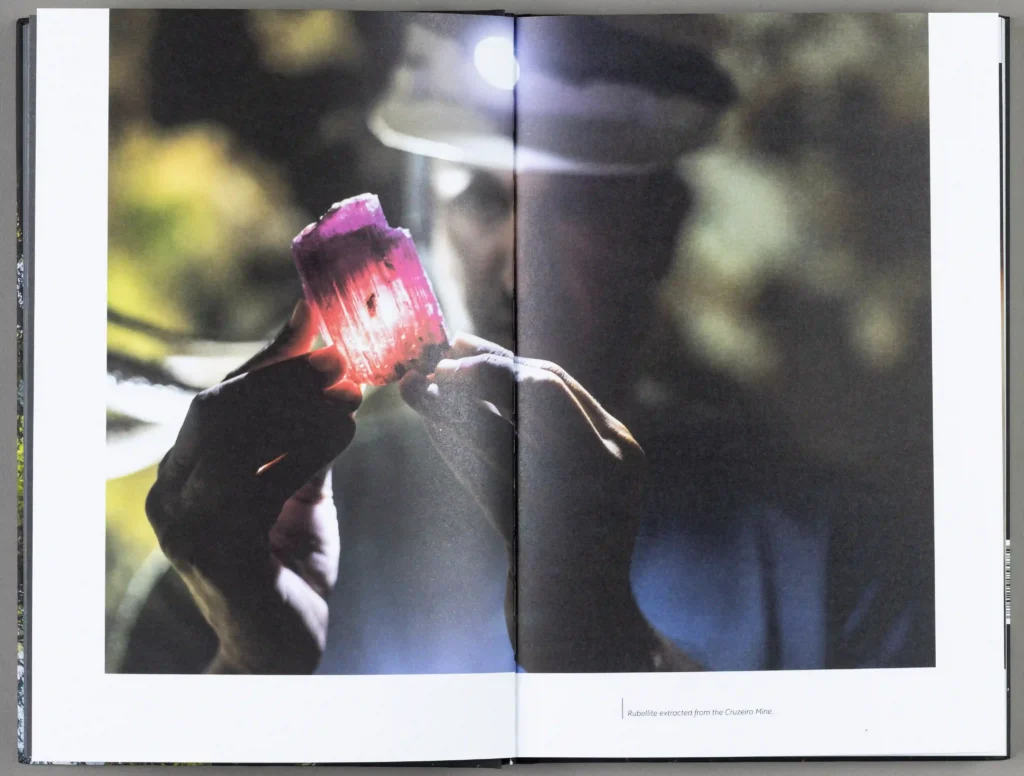 Livro Mina do Cruzeiro aberto em foto de minerador com turmalina