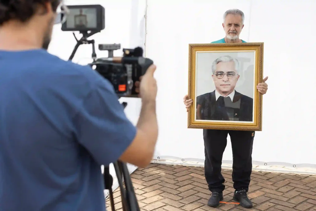 Projeto Moradores: cinegrafista filma morador segurando seu retrato emoldurado