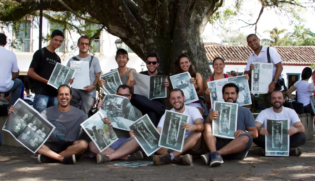 ND: novas possibilidades narrativas: participantes da oficina seguram suas fotos sob árvore