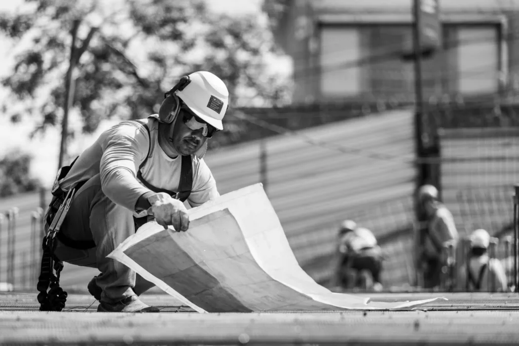 Relatório MRV&CO: operário de capacete consulta planta da obra