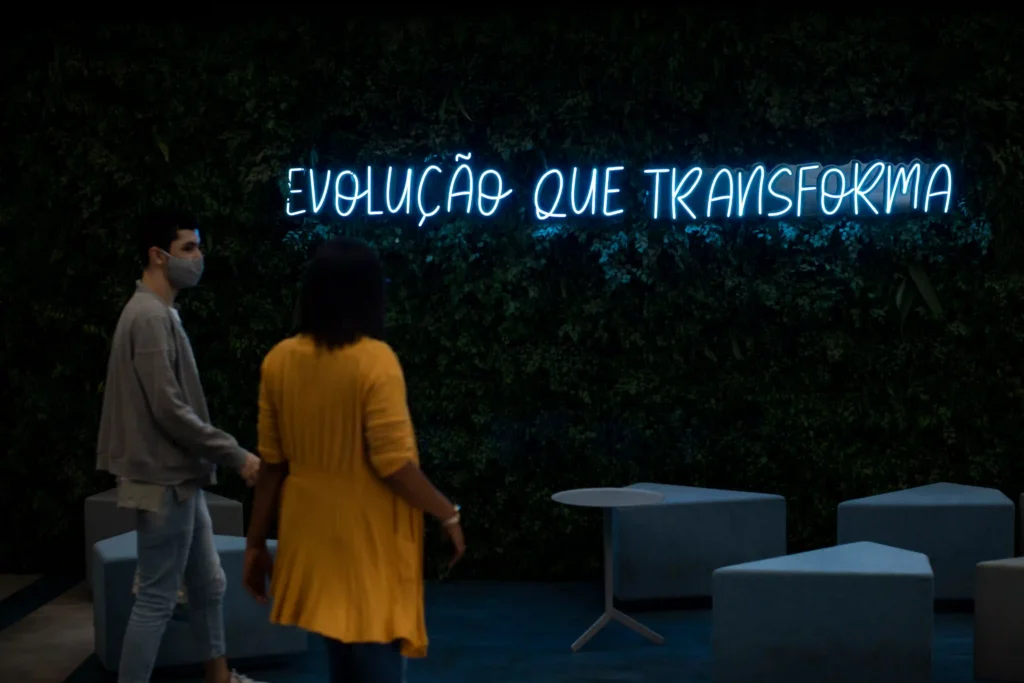 AEC: colaboradores diante de letreiro neon Evolução que transforma